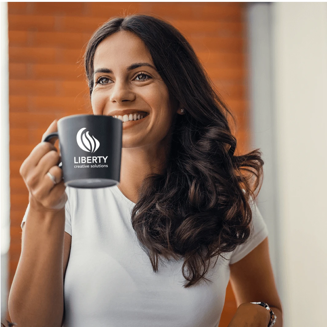 Woman drinking out of a Liberty Creative Solutions coffee mug.